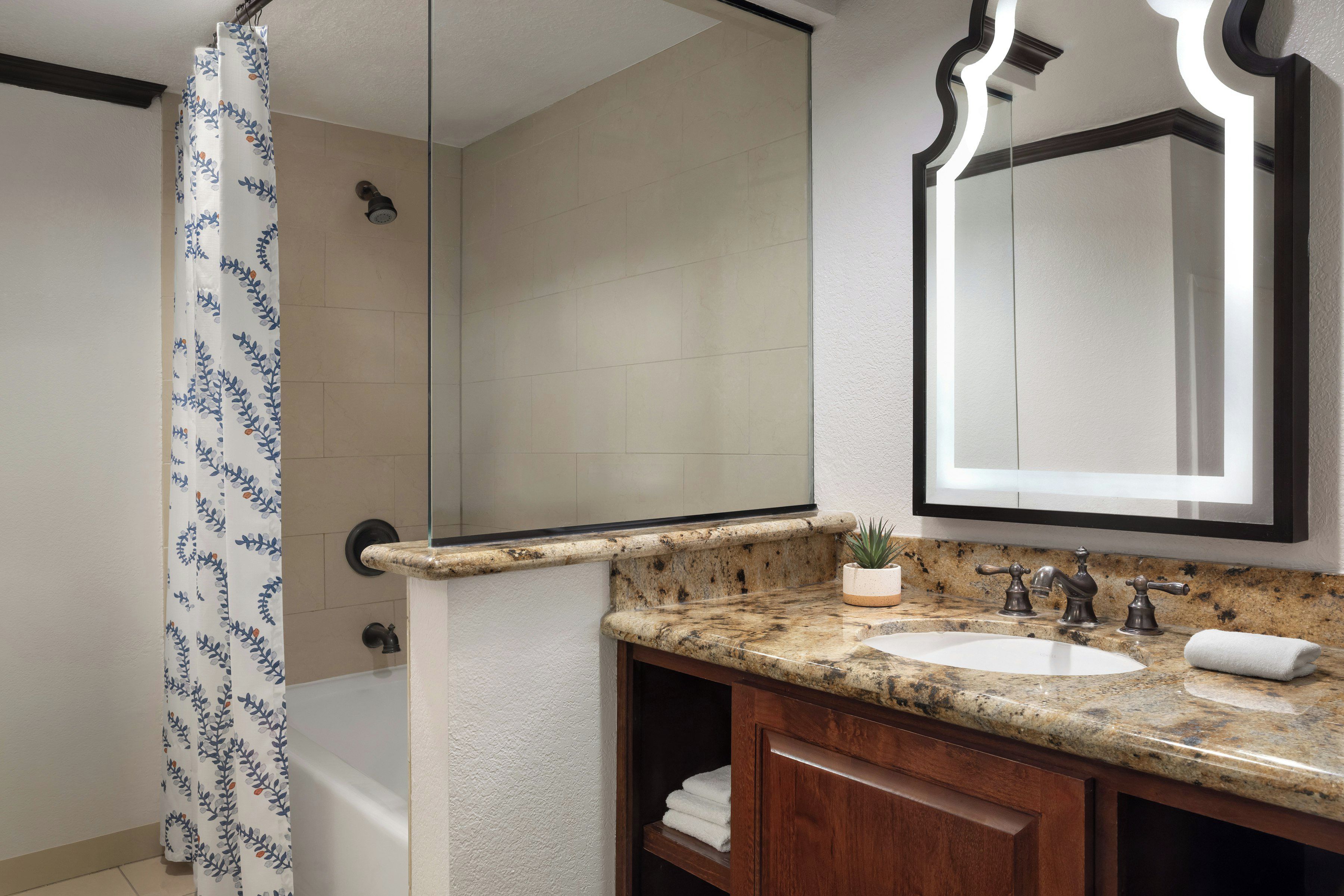 A bathroom with a shower, a sink, a mirror, and a towel rack.