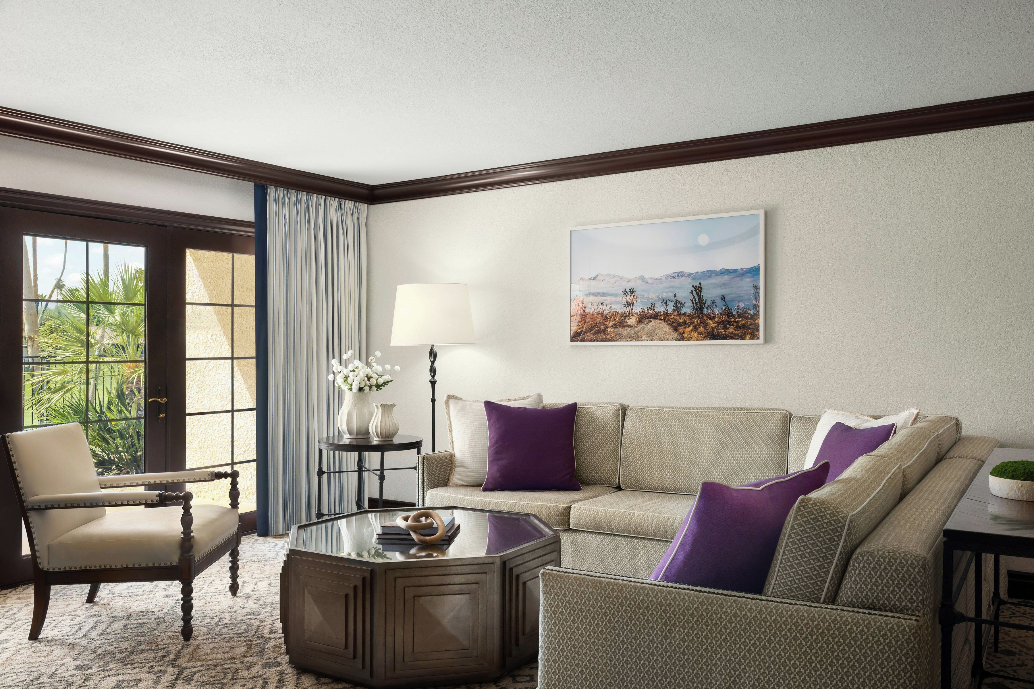 A living room with a sofa, armchair, coffee table, and a painting on the wall.