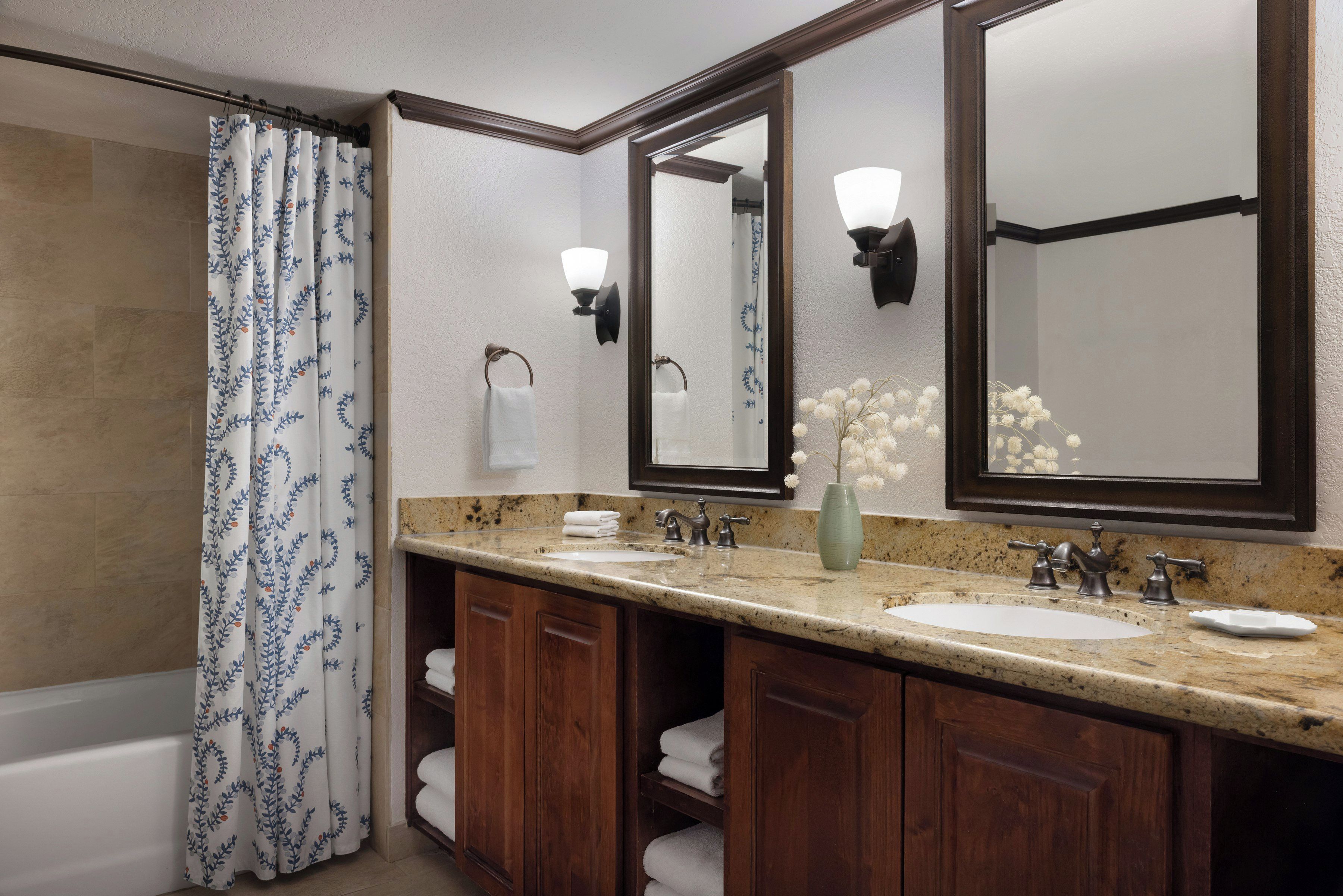 A bathroom with a double sink, a large mirror, a towel rack, and a shower curtain.