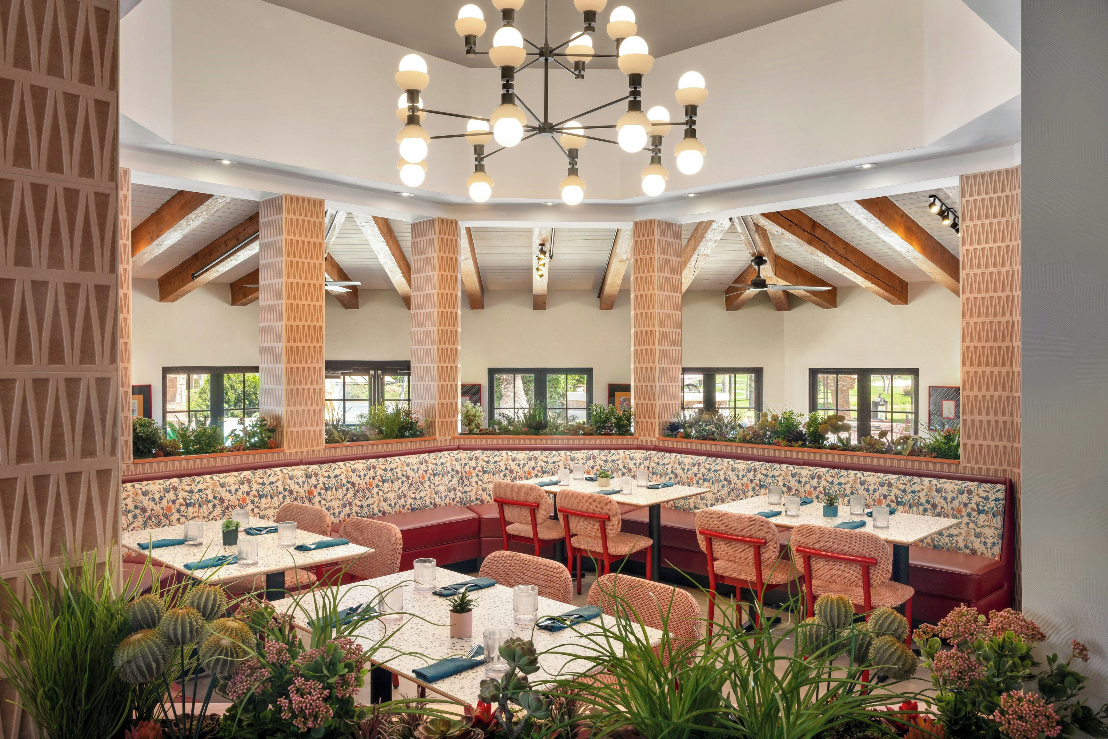 A restaurant with high ceilings, exposed beams, and a central seating area with tables and chairs.
