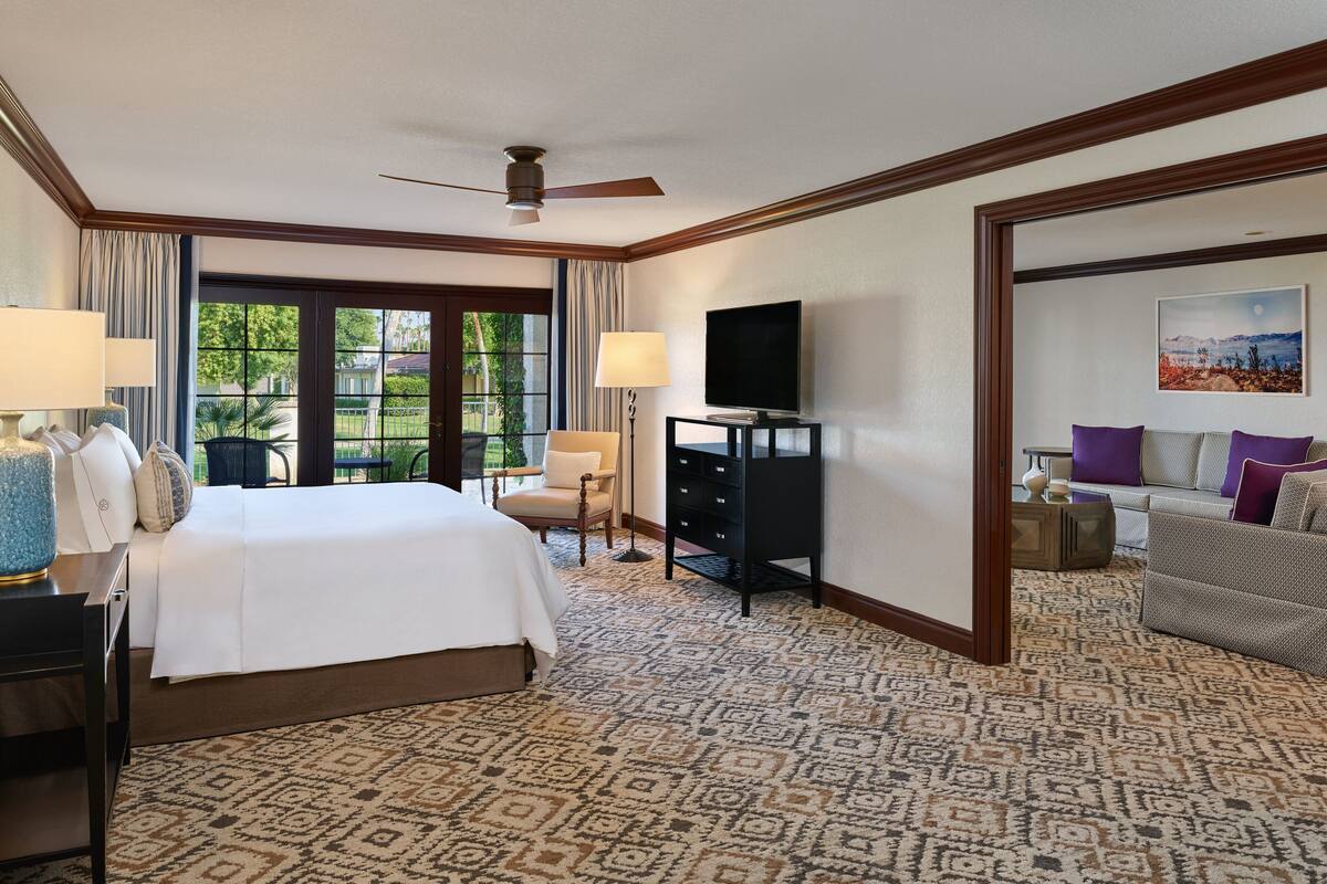 Habitación de hotel con una cama grande, televisión, escritorio y una silla.