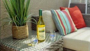 A wicker table with a bottle of wine, a glass, and a potted plant. - Inn By The Sea La Jolla (La Jolla)