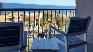 A balcony with two chairs and a small table, overlooking a coastal area with buildings and a clear sky. - Inn By The Sea La Jolla (La Jolla)
