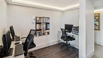A modern office space with multiple computer workstations, a bulletin board with various items, and a printer.