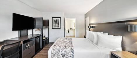 Ein modernes Hotelzimmer mit Bett, Schreibtisch mit Stuhl, Flachbildfernseher und einem großen Spiegel.