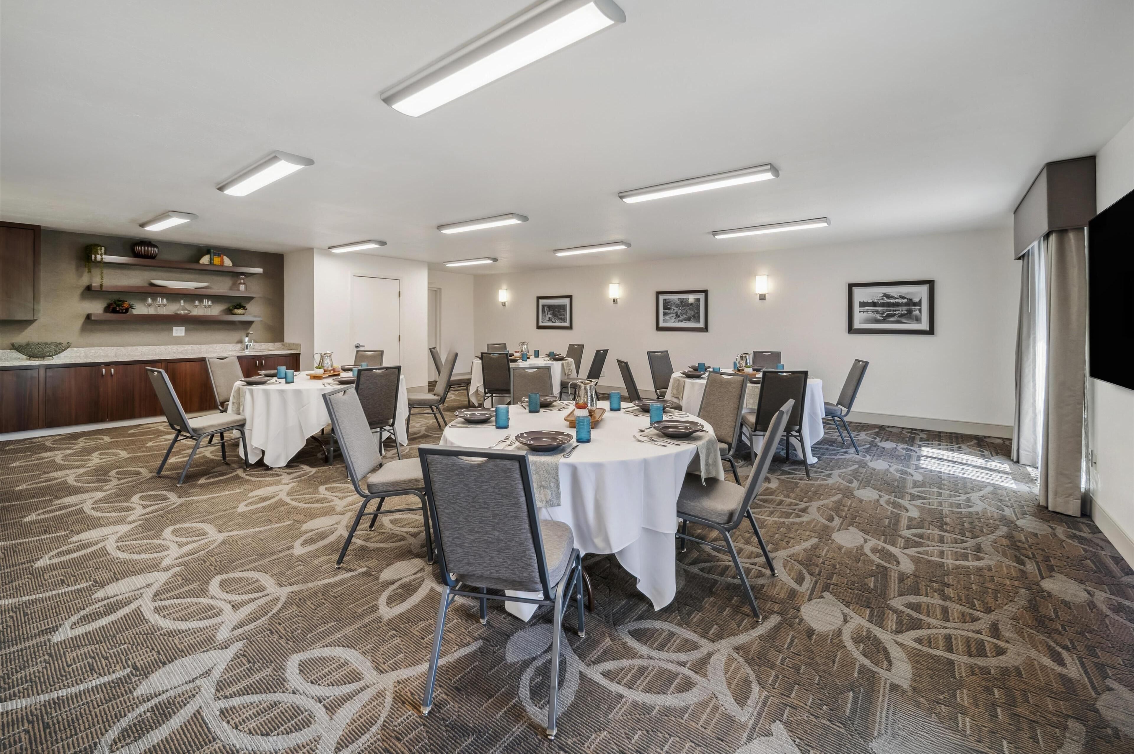 A conference room with round tables, chairs, and a buffet area.