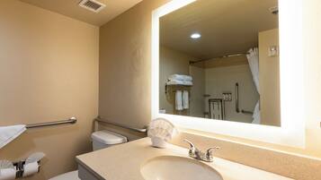 A bathroom with a sink, toilet, and a large mirror.