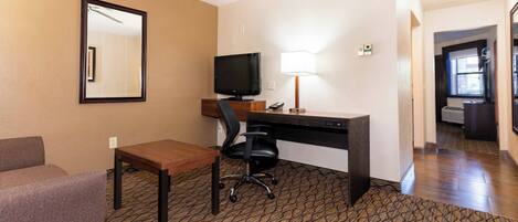 Habitación de hotel con escritorio, silla, televisión y espejo.