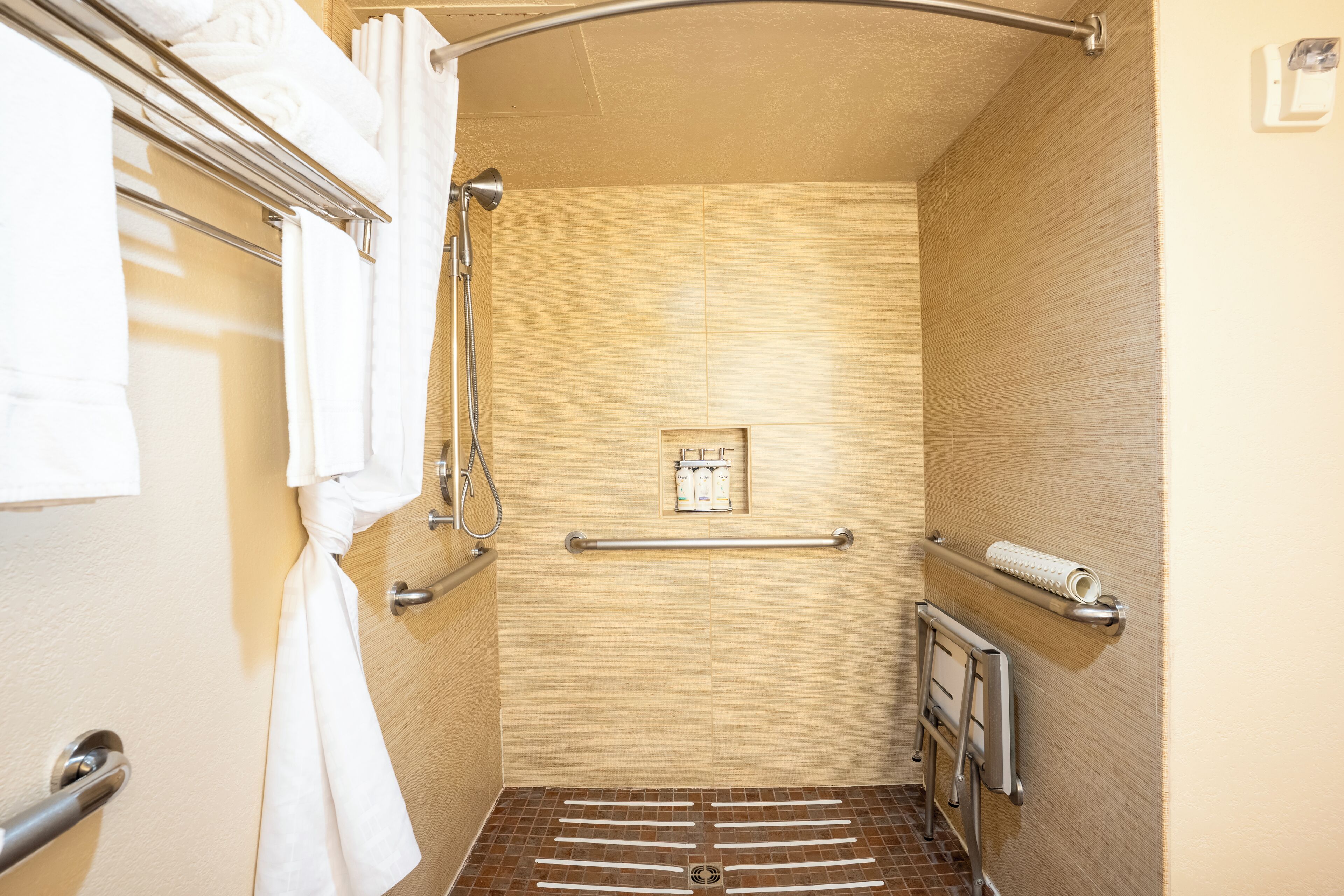 Un espace douche équipé d’une barre d’appui, d’un porte-serviettes et d’une petite étagère pour les articles de toilette.