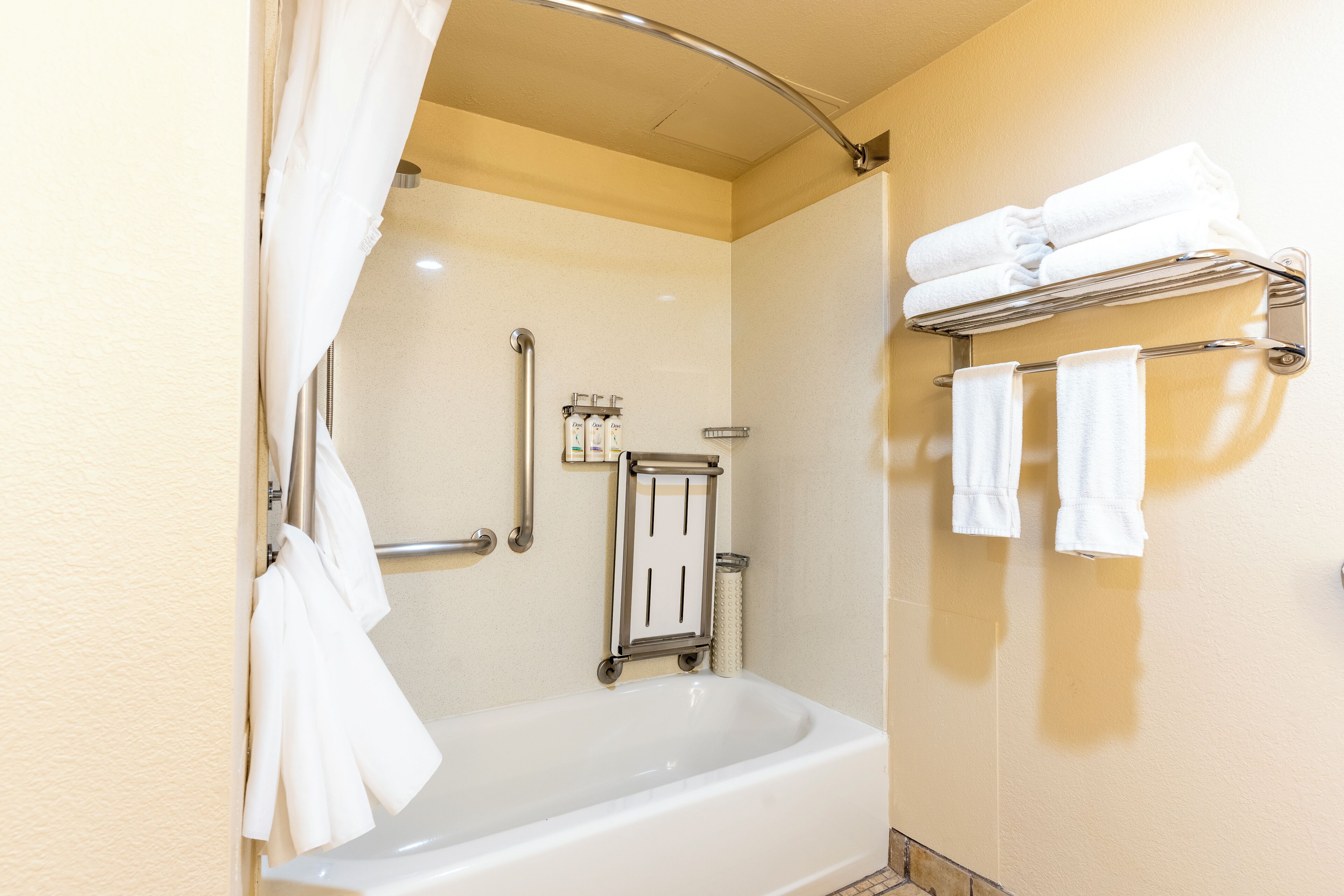 Une salle de bain équipée d’une baignoire, d’un rideau de douche, d’un porte-serviettes et d’une barre d’appui.