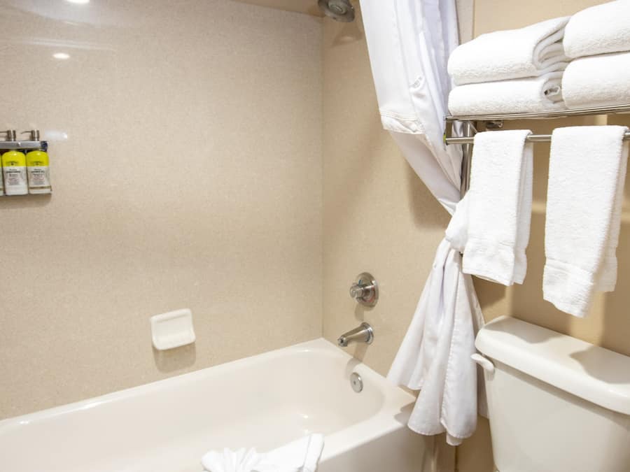 Un baño con bañera, inodoro y un perchero con toallas dobladas.