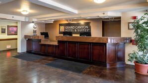 Un comptoir d’accueil à l’hôtel Grand Canyon, doté d’une horloge numérique, d’un téléviseur à écran plat et d’une plante en pot.