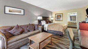A hotel room with a bed, a sofa, a desk, and a chair. - Quality Inn Windsor Mill - Baltimore (Windsor Mill)