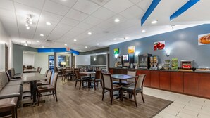 A spacious restaurant with multiple dining tables and booths, a counter with a menu display, and a blue accent wall. - Quality Inn Windsor Mill - Baltimore (Windsor Mill)