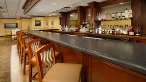 A bar area with a long counter, multiple chairs, and a variety of liquor bottles. - Quality Inn Windsor Mill - Baltimore (Windsor Mill)