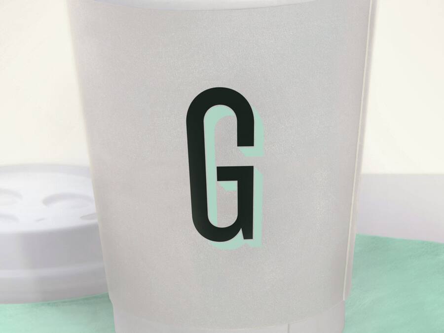 A white cup with a black 'G' logo, placed on a green napkin.
