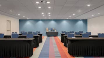 A conference room with a long table, chairs, a podium, and a carpeted floor.