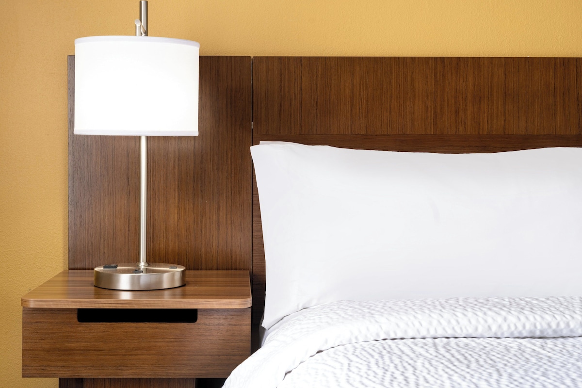 Un lit bien fait, avec un oreiller blanc et une tête de lit en bois.