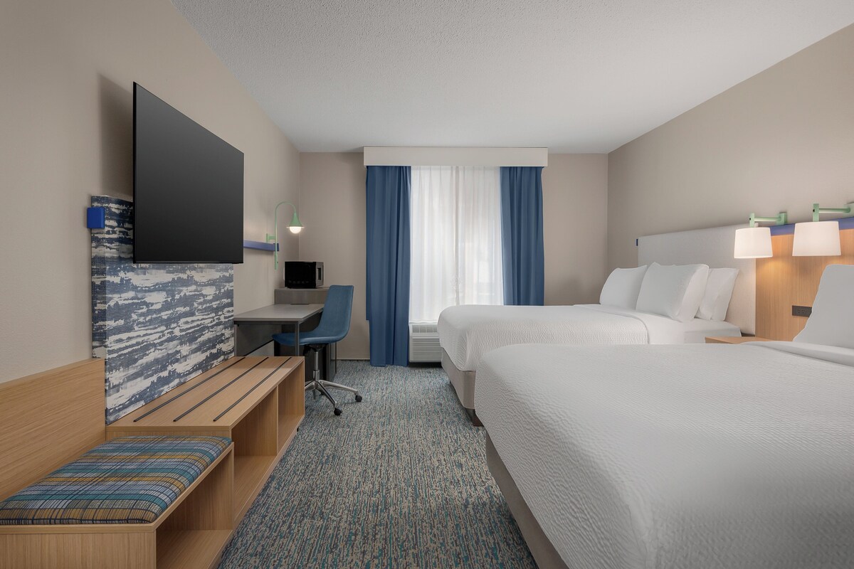 Une chambre d’hôtel équipée d’un lit, d’un bureau, d’une chaise et d’une télévision.