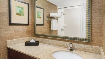 A bathroom with a granite countertop, a white sink, a towel rack, and framed artwork on the wall.