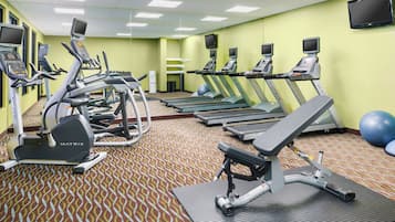 Un gimnasio con cintas de correr, elípticas y pelotas de ejercicio.