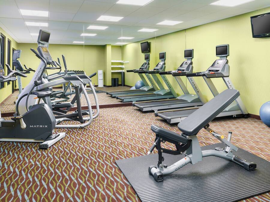 Un gimnasio con cintas de correr, elípticas y pelotas de ejercicio.