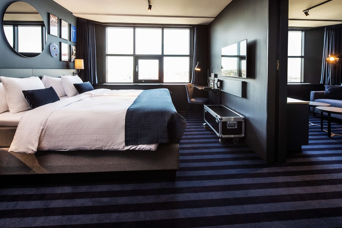Una habitación de hotel moderna con una cama grande, un escritorio, una silla y un televisor.