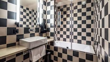 A modern bathroom with a checkered black and white tile pattern, a white sink, and a glass-enclosed shower area.