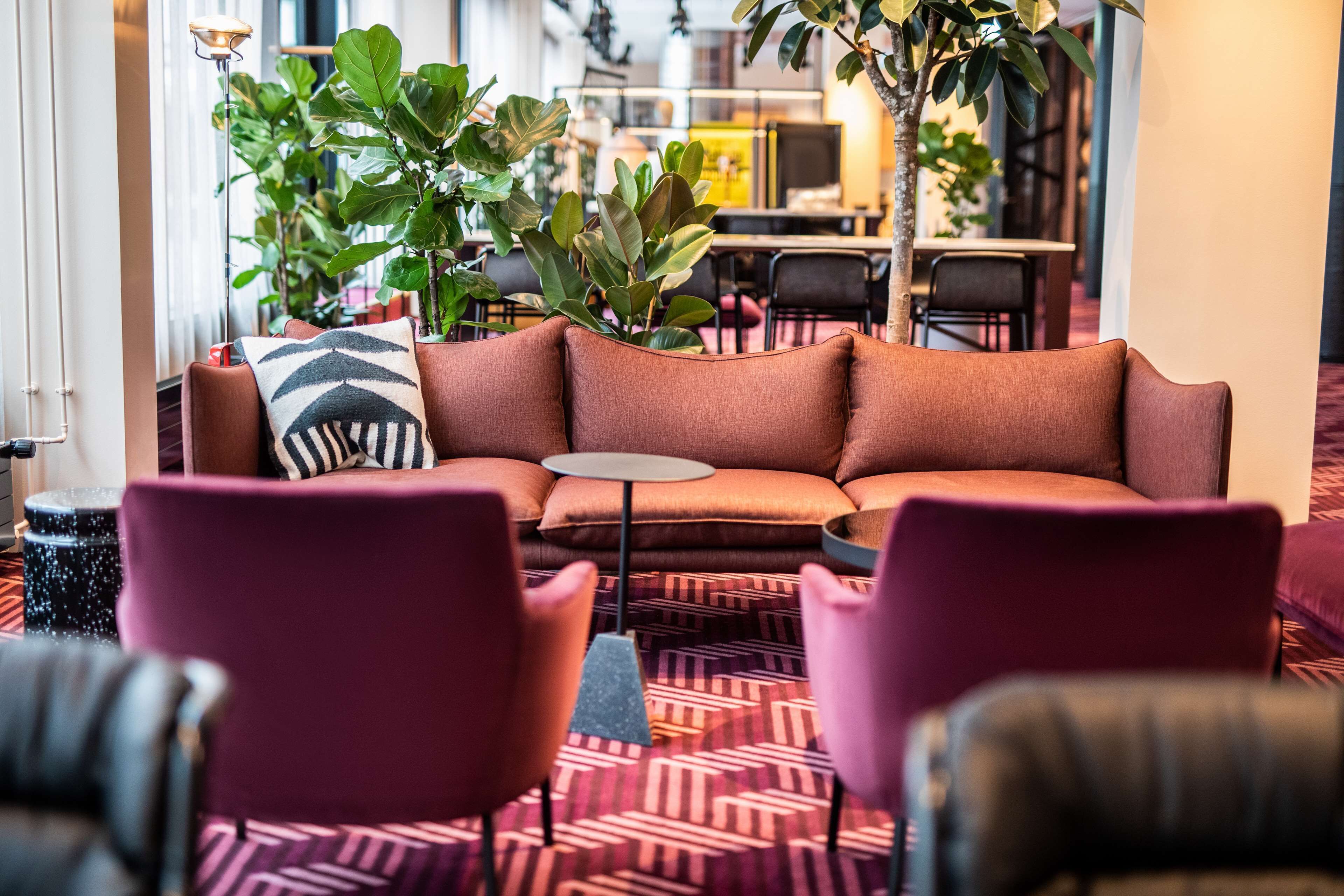 A modern lounge area with a sofa, armchairs, and a patterned carpet.