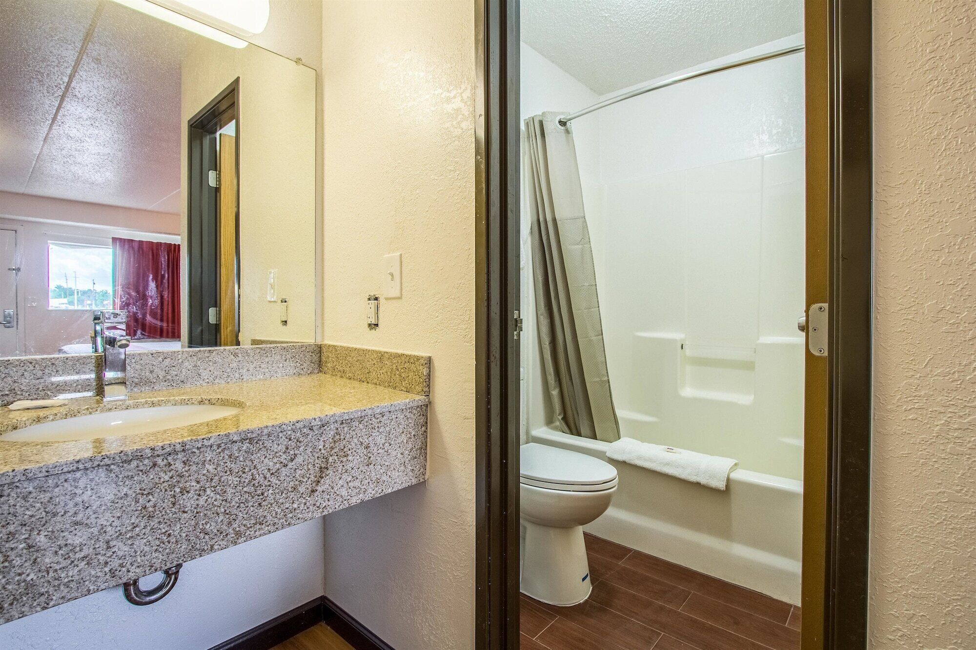 A bathroom with a granite countertop, a white toilet, and a glass shower enclosure.