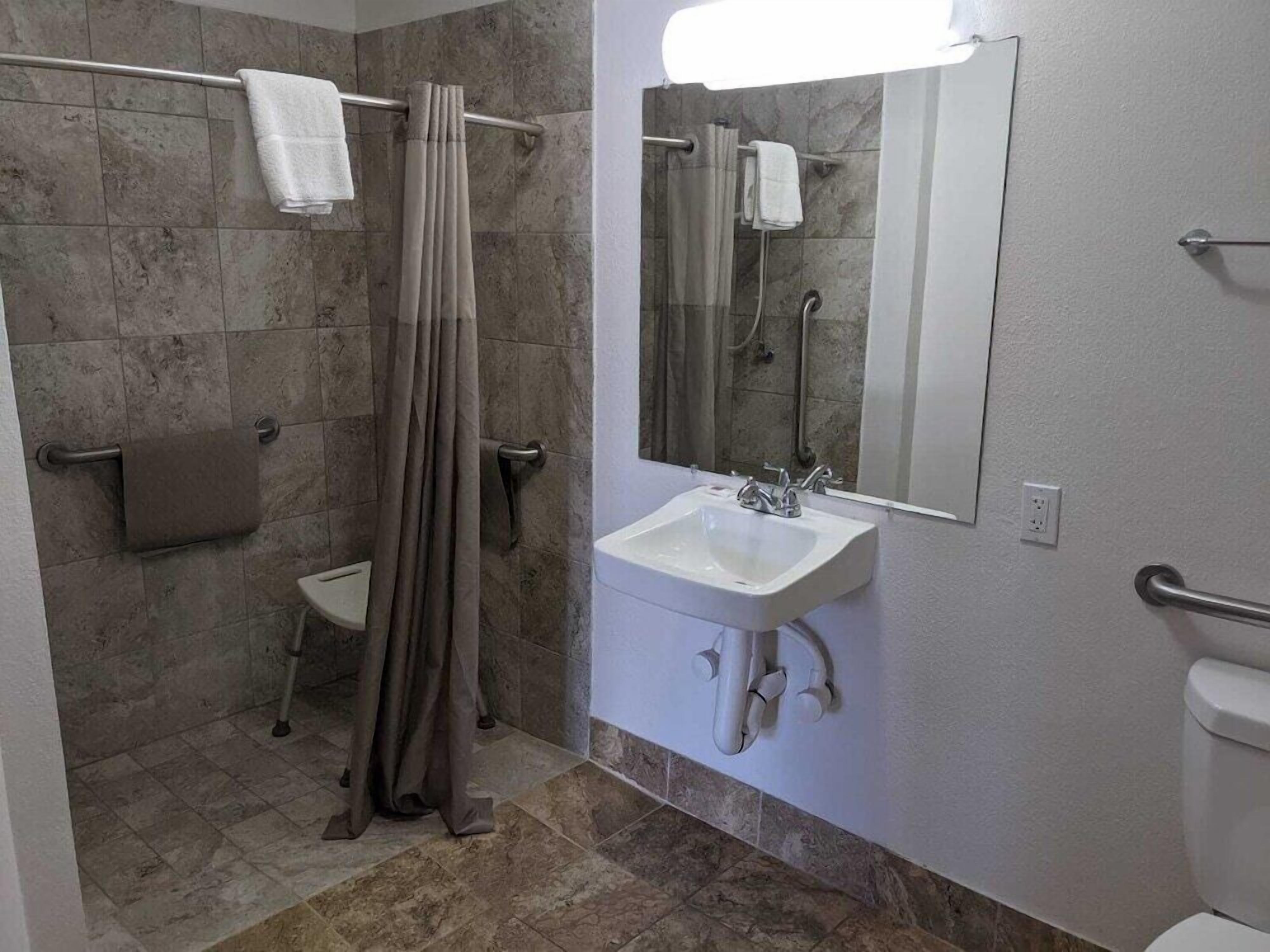 Un baño con ducha, lavabo, inodoro y espejo.