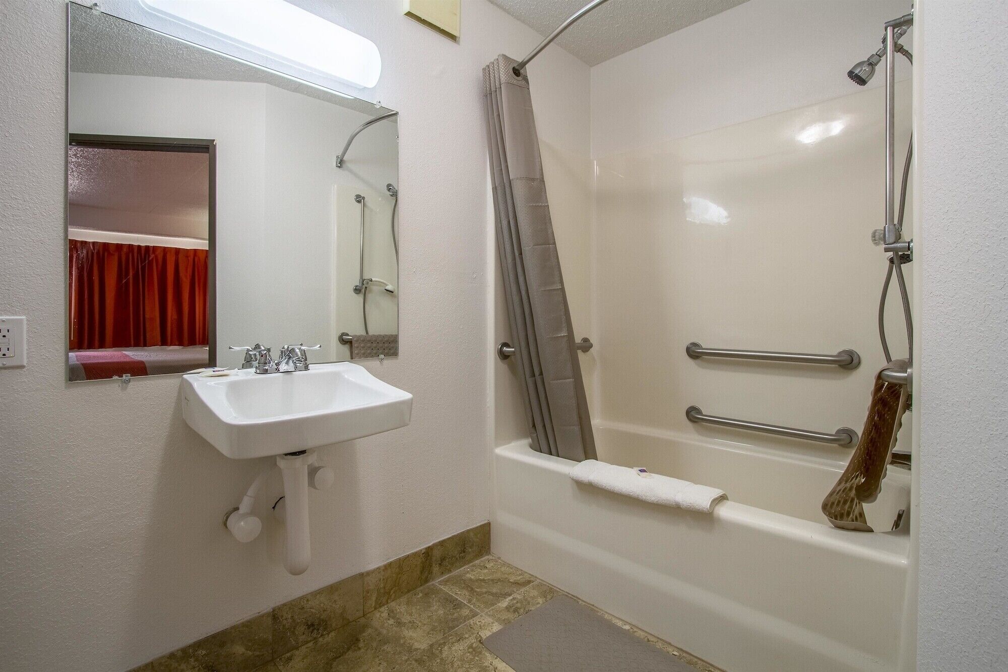 Een badkamer met een wit wastafel, spiegel en bad.