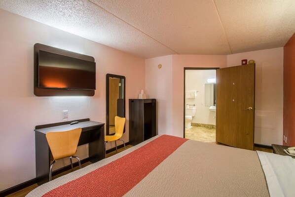 A hotel room with a bed, a desk with a chair, a television, a mirror, and a wardrobe. - Motel 6 Ashland, OH (Ashland)