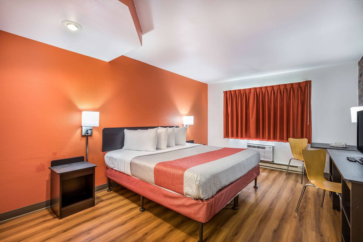 A hotel room with a bed, bedside tables, a desk, and a chair.