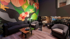 Un área de descanso moderna con un gran mural abstracto, asientos cómodos y una zona de bar.