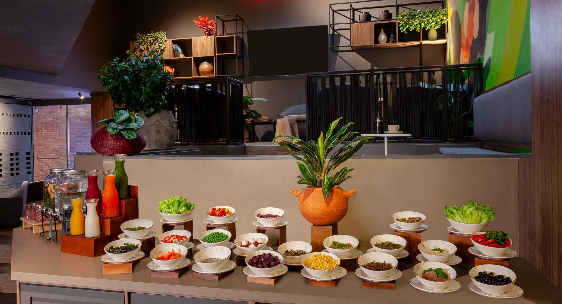 Montaje de bufé con diferentes alimentos y una planta grande en maceta.