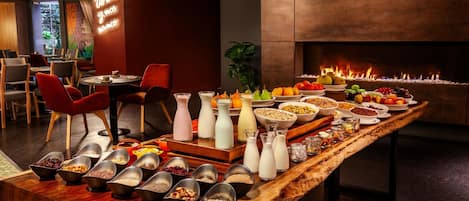 A buffet setup with various food items and beverages, a fireplace, and seating arrangements.