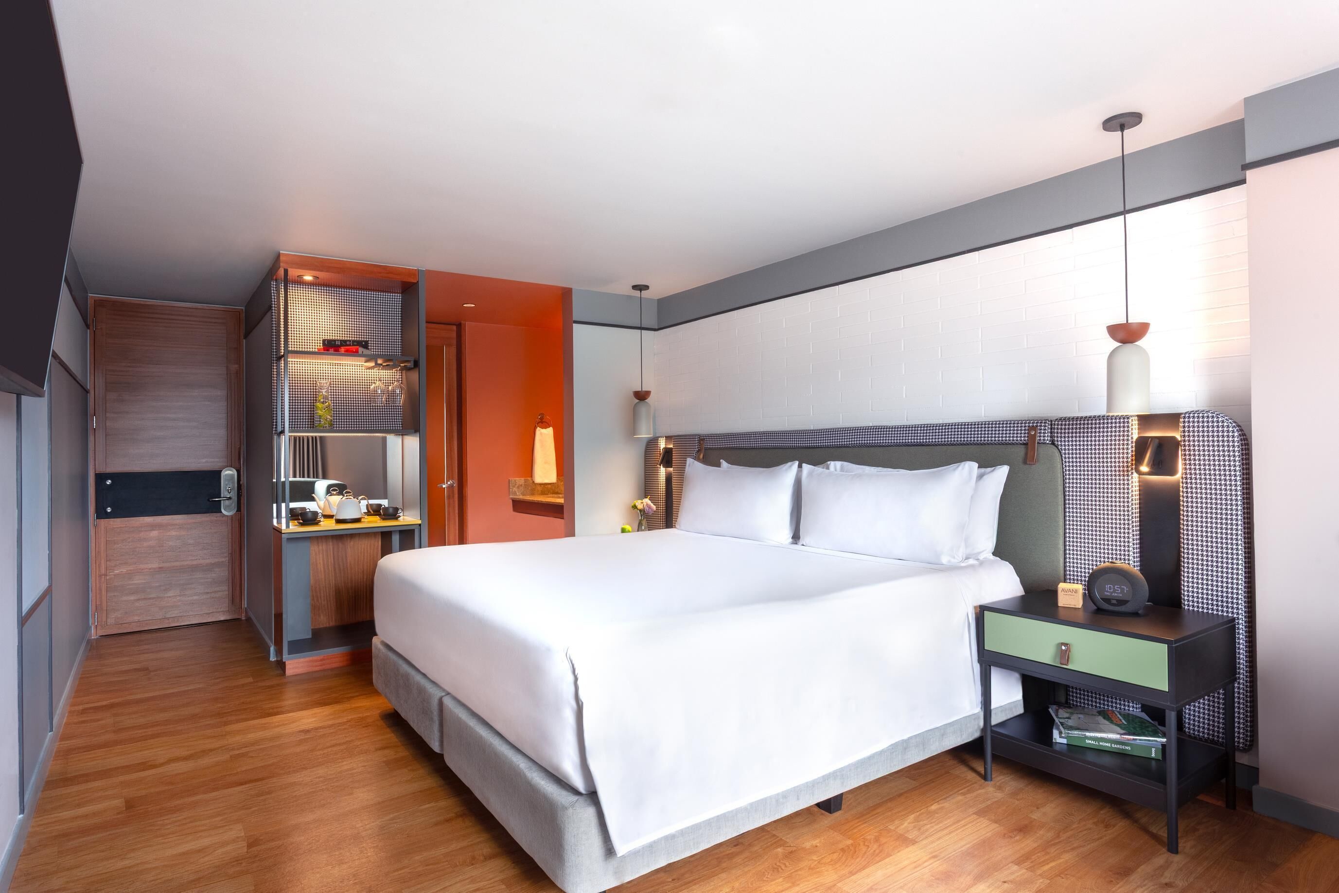Una habitación de hotel moderna con una cama grande, mesitas de noche, un armario y un baño.