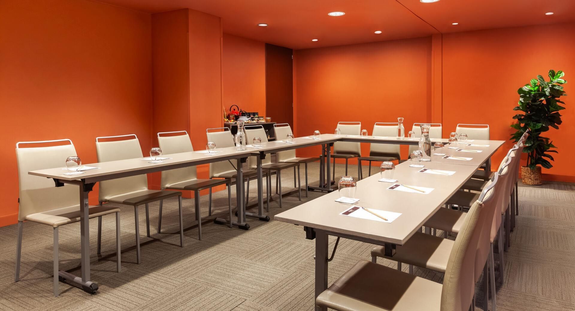 A conference room with a long table, chairs, and a potted plant.