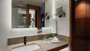 Une salle de bain moderne avec un comptoir en granit, un robinet noir, un grand miroir et une porte en bois.