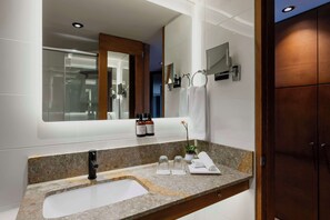 Een moderne badkamer met een granieten aanrecht, een zwarte kraan, een grote spiegel en een houten deur.