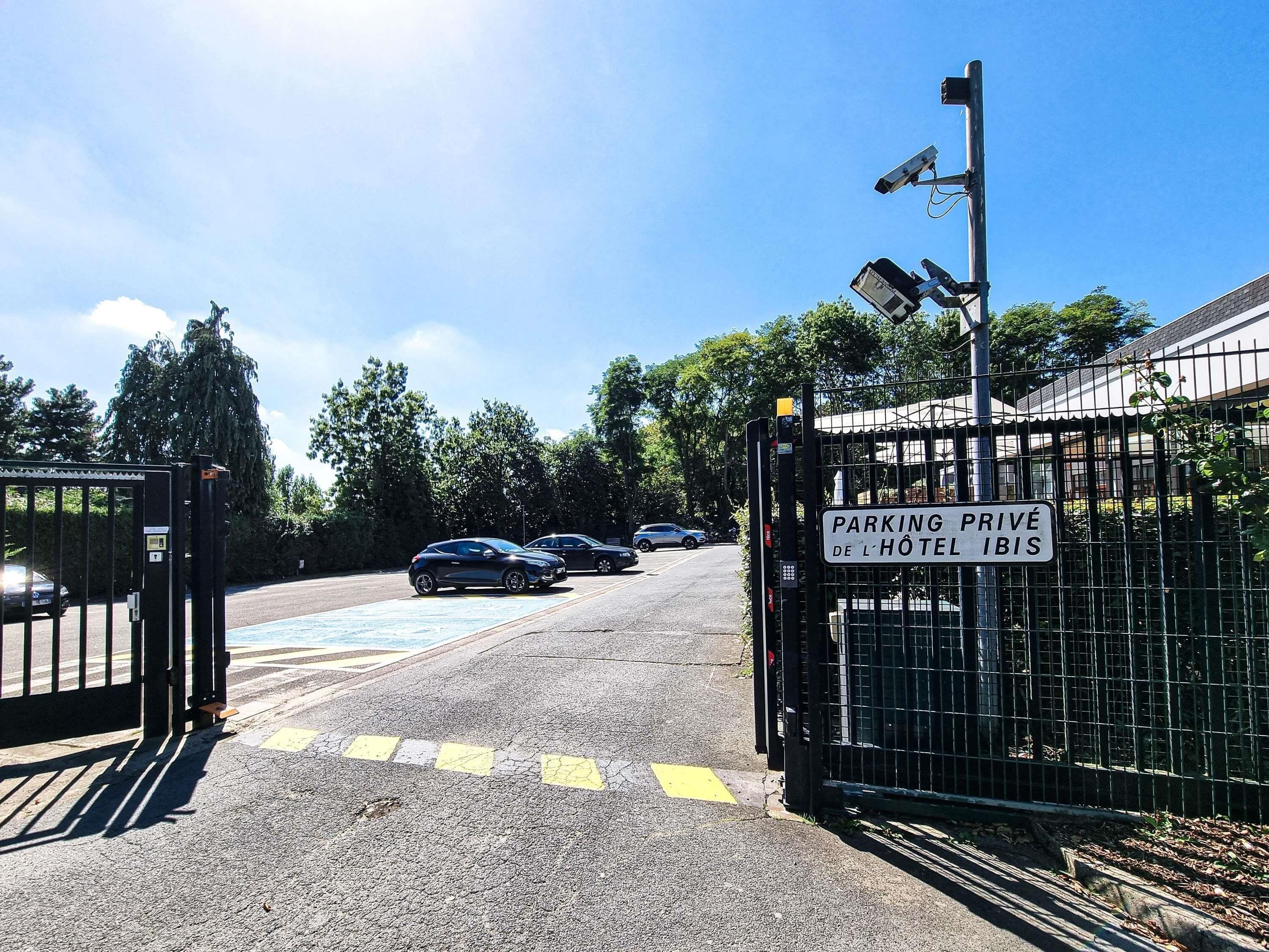 A gated entrance to a hotel with a sign indicating private parking.