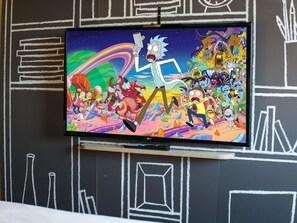 A television displaying an animated scene with characters in a colorful, chaotic environment. - ibis Caen Porte d'Angleterre (Herouville-Saint-Clair)