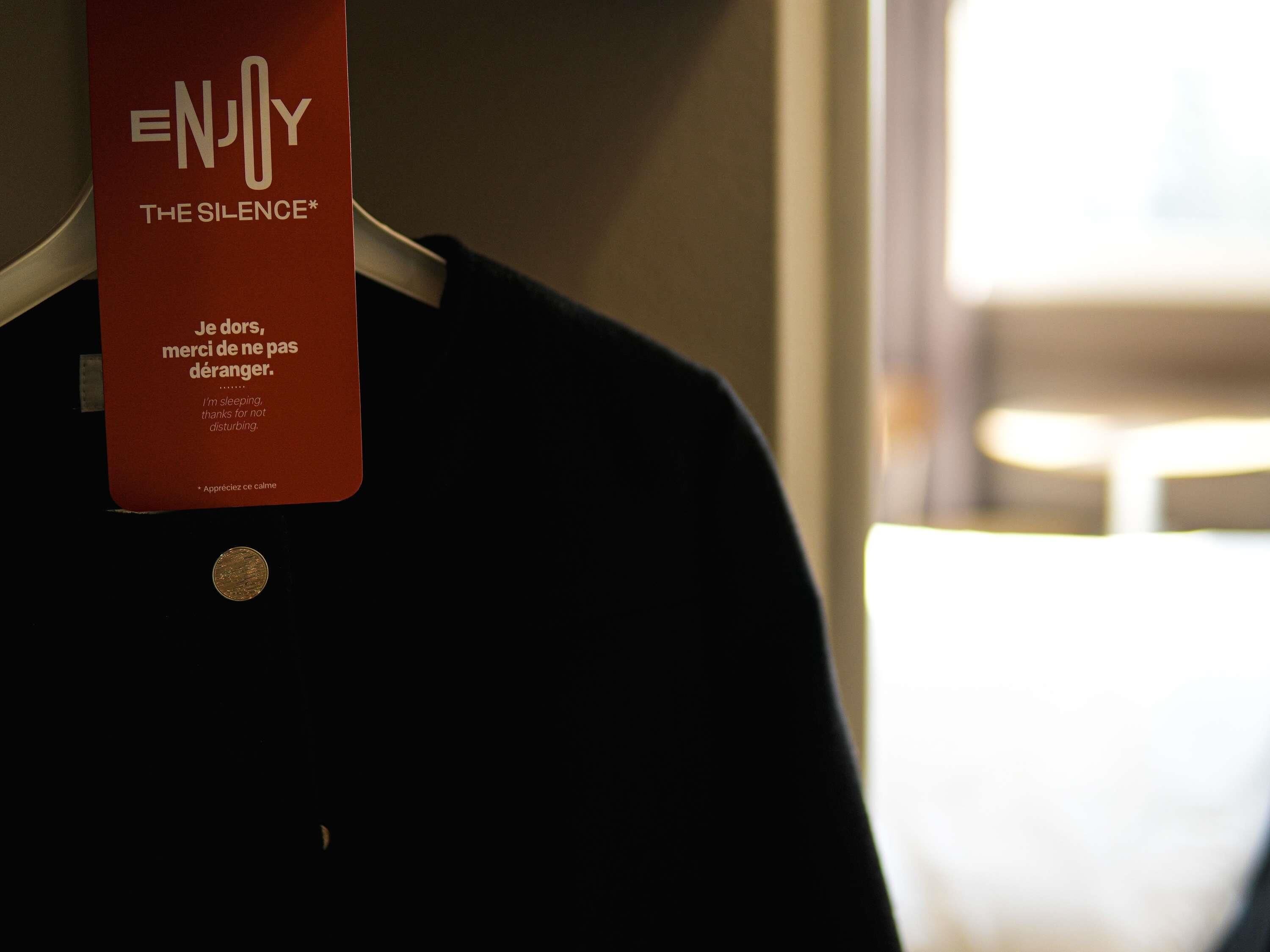 A hotel sign with 'ENJOY THE SILENCE' and a message in French.