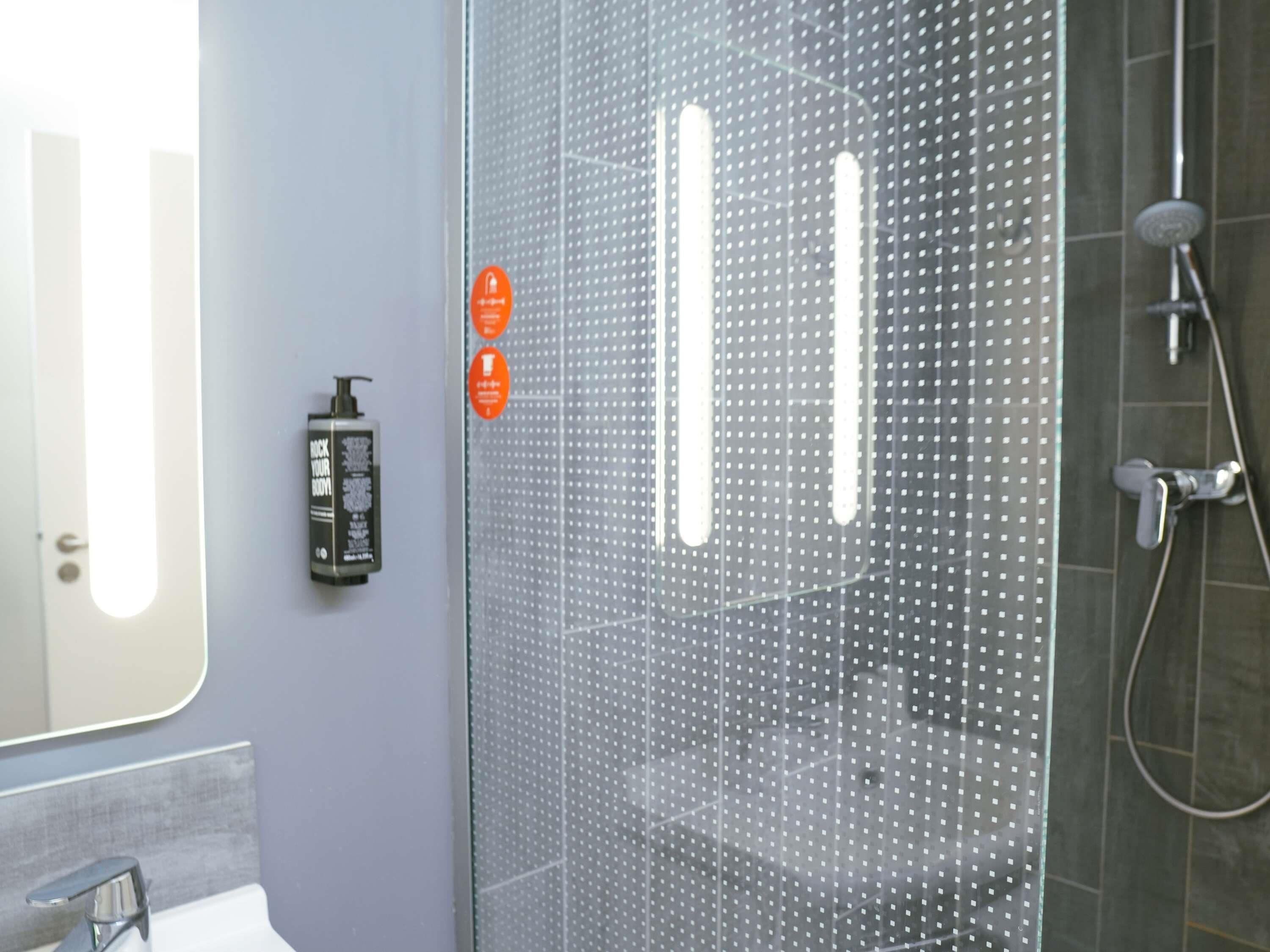 Une salle de bain moderne avec une douche à parois de verre, un lavabo et un miroir.