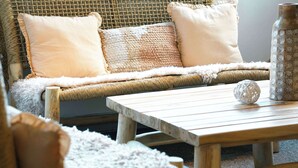 A wicker sofa with cushions, a white fluffy throw, and a wooden coffee table with a decorative ball and vase. - ibis Caen Porte d'Angleterre (Herouville-Saint-Clair)