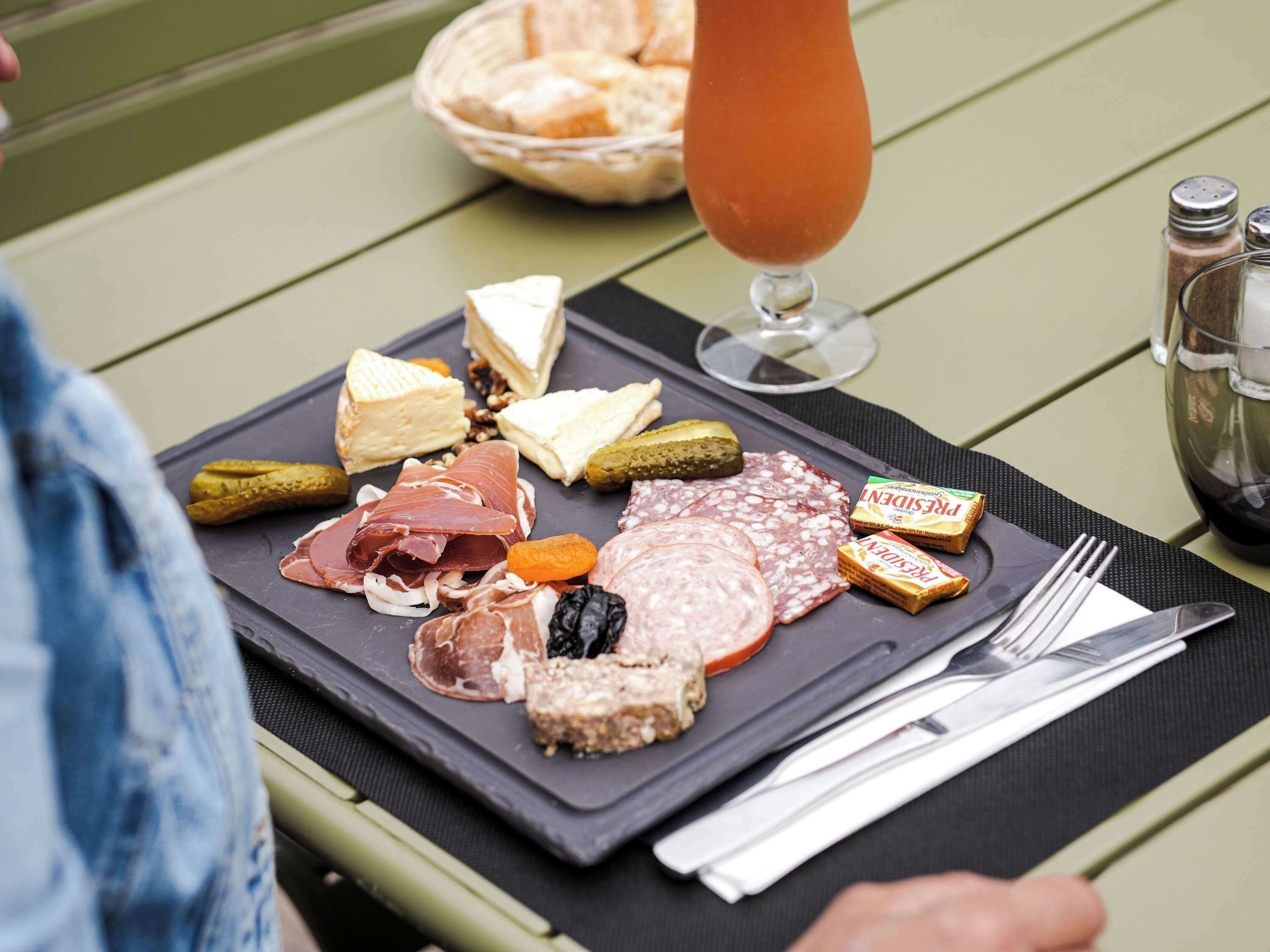 A charcuterie board with various meats, cheeses, and pickles on a table.