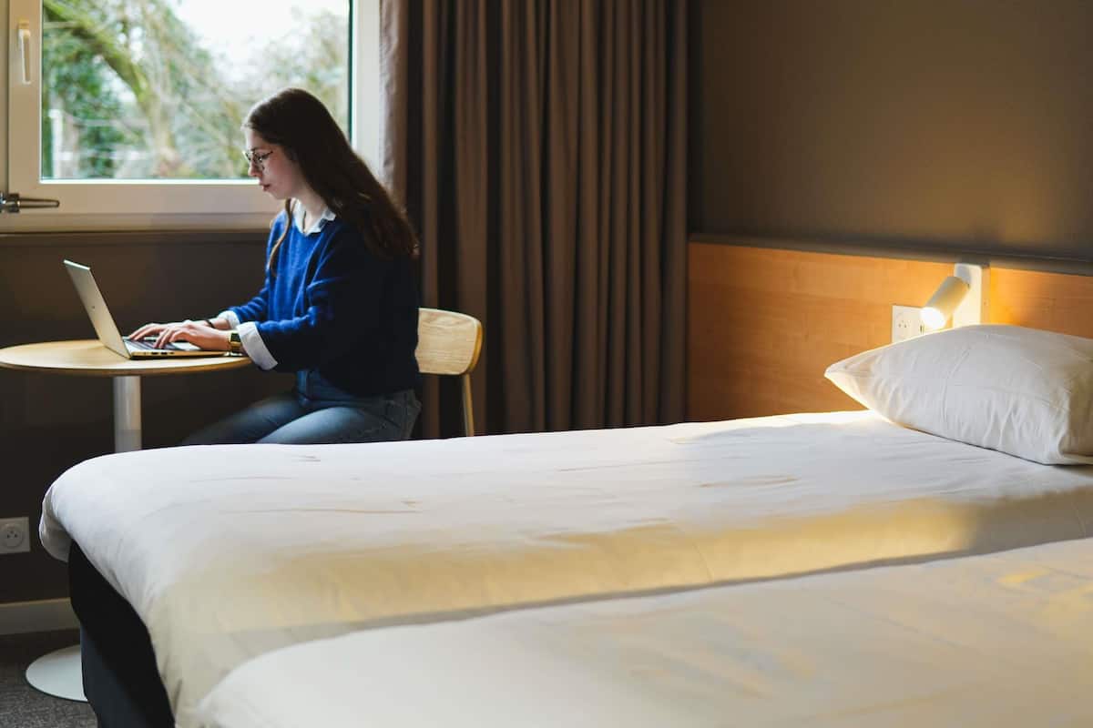 Une chambre d’hôtel avec un lit, un bureau et un ordinateur portable.