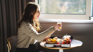 A person sitting at a round table with a glass of orange juice, a basket of pastries, and a cup of coffee. - ibis Caen Porte d'Angleterre (Herouville-Saint-Clair)