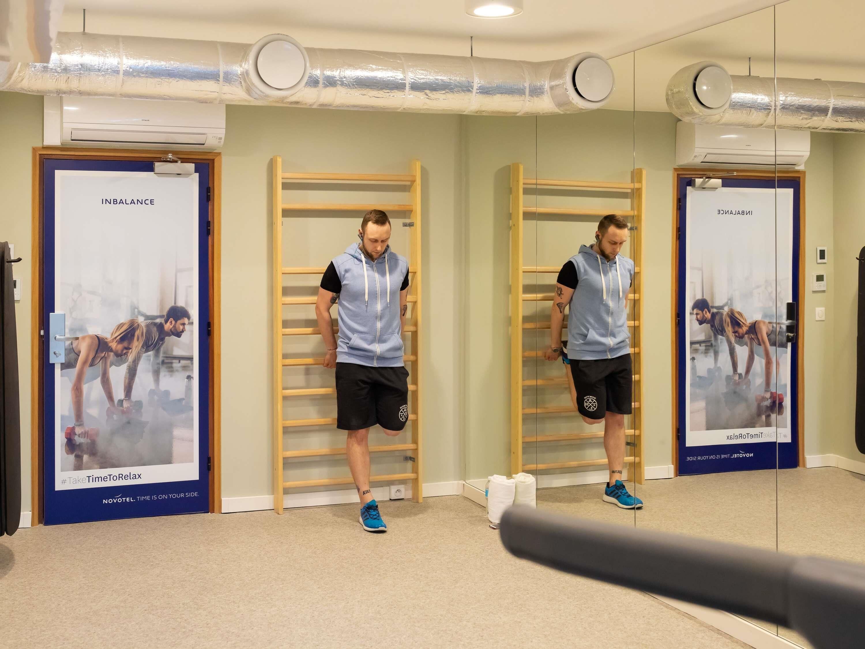 A gym with exercise equipment, wooden racks, and mirrored walls.